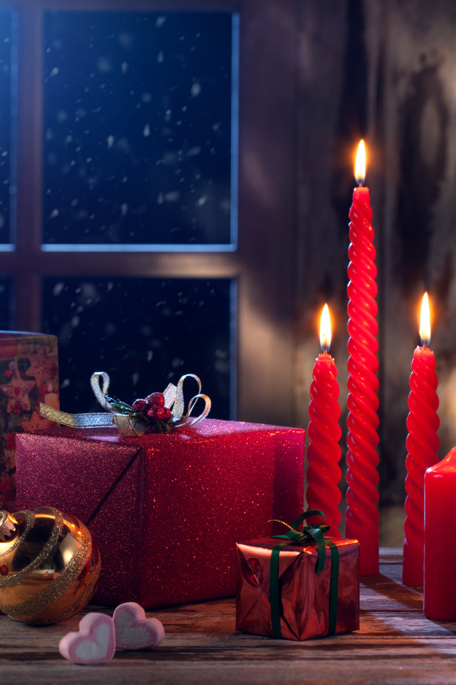 Зажженные красные свечи с подарками и игрушками на Новый год 2018