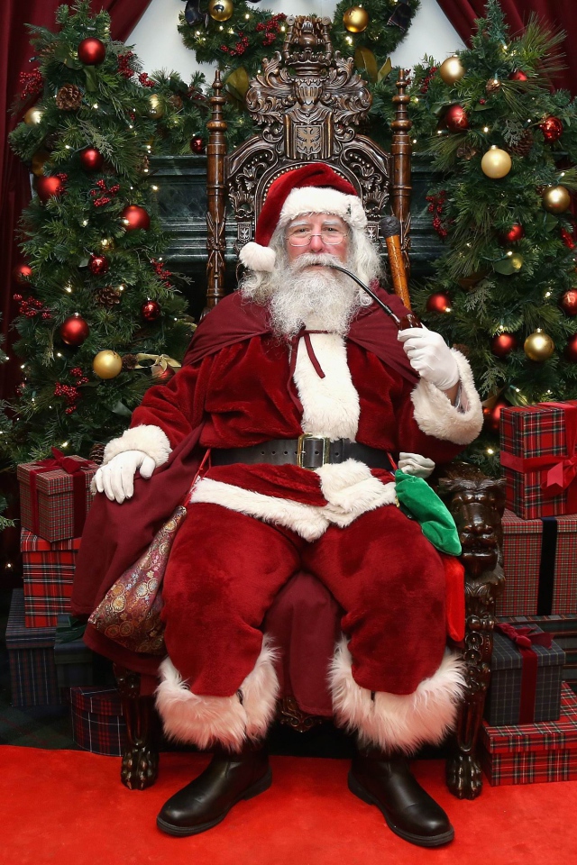 Санта Клаус курит трубку сидя в кресле