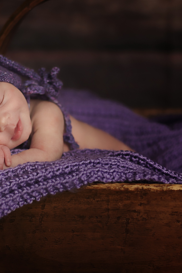 Грудной ребенок спит в деревянной корзине