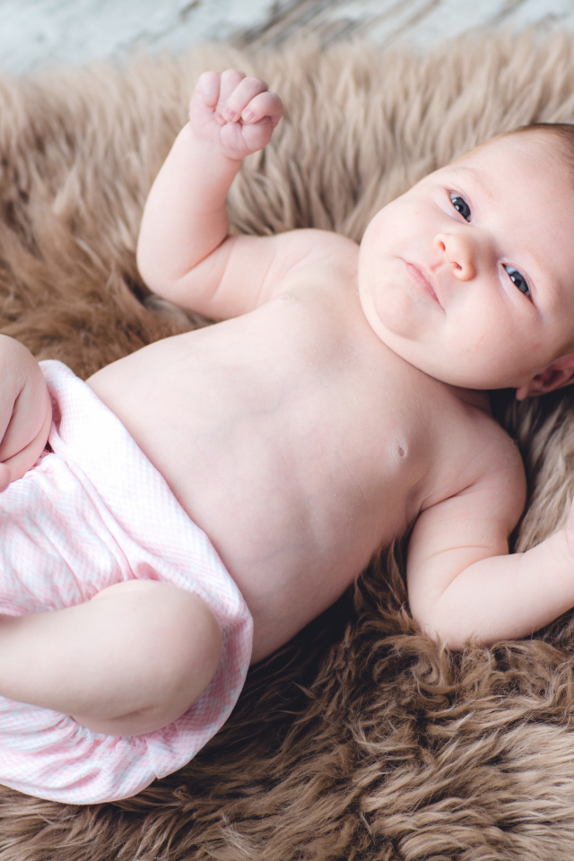 Грудной ребенок лежит на меховом покрывале