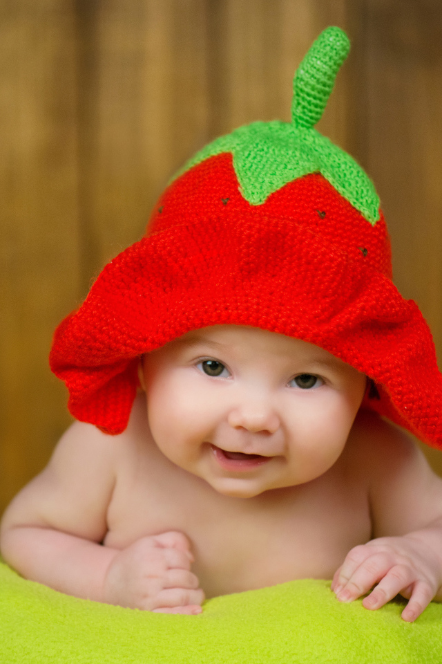 Младенец в забавной шапке клубнике на голове