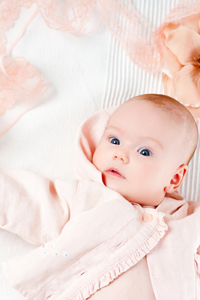 Младенец в розовом наряде с большим цветком у головы