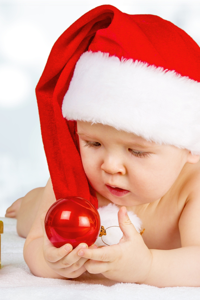 Младенец в красной новогодней шапке с елочными шарами на новый год