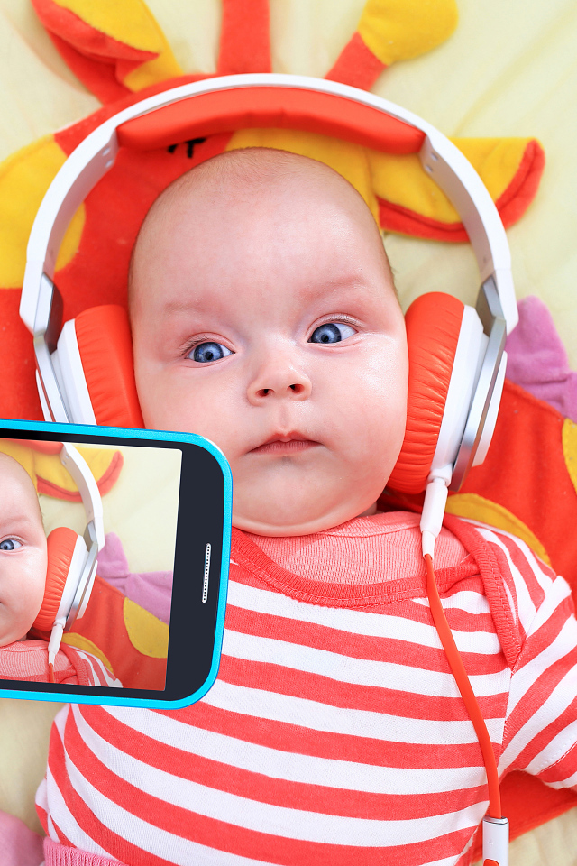 Младенец в оранжевых наушниках делает селфи