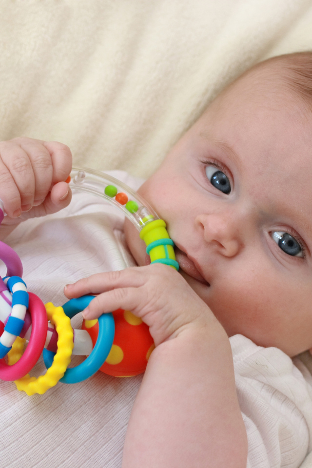 Грудной ребенок с погремушкой в руках