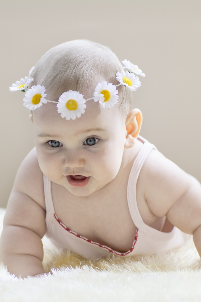 Грудной ребенок с венком из белых ромашек на голове