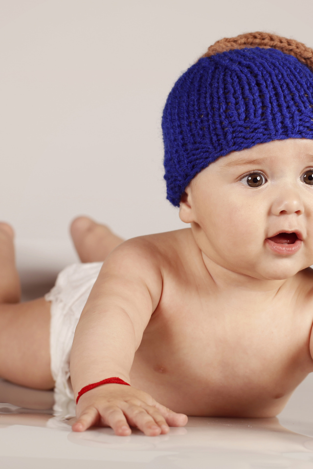 Грудной кареглазый ребенок в вязаной шерстяной шапке