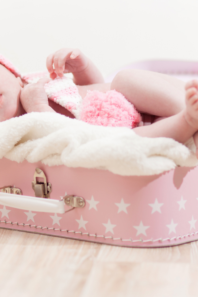 Милый младенец лежит в розовом чемодане