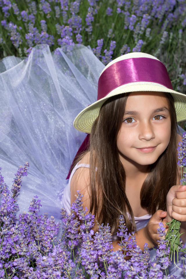 Девочка в шляпе лежит в фиолетовых цветах лаванды