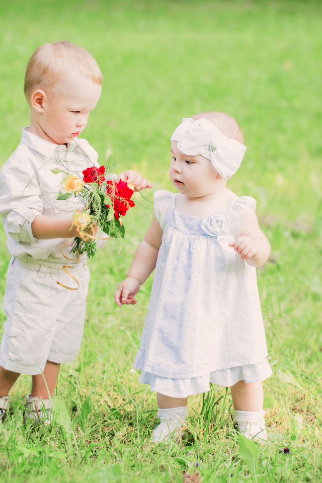 Маленький мальчик дарит букет полевых цветов девочке