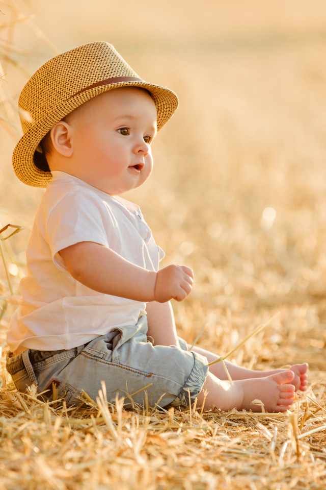 Маленький мальчик в шляпе сидит на себе
