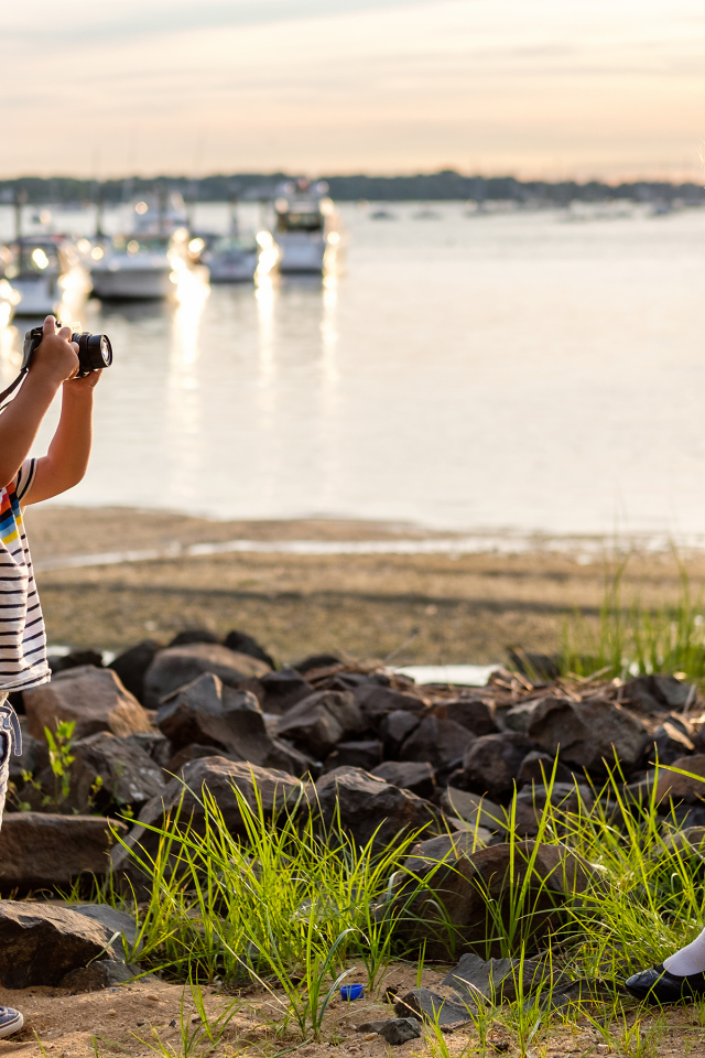 Маленький мальчик фотографирует девочку на берегу