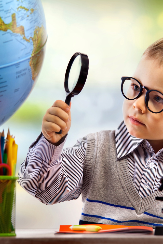 Маленький мальчик в очках исследует глобус