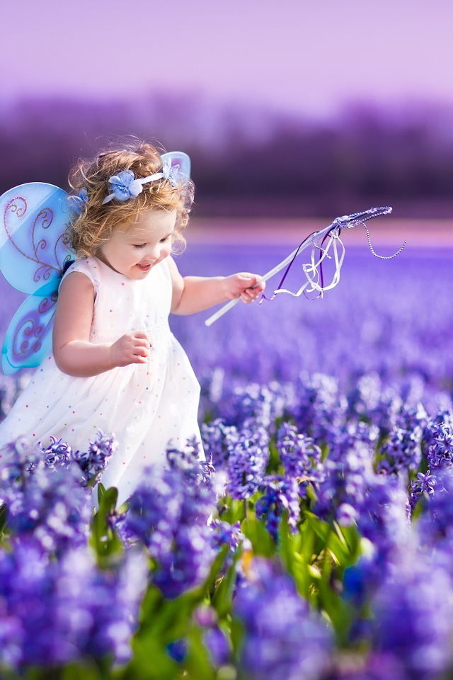 Маленькая девочка в костюме феи гуляет по полю гиацинтов