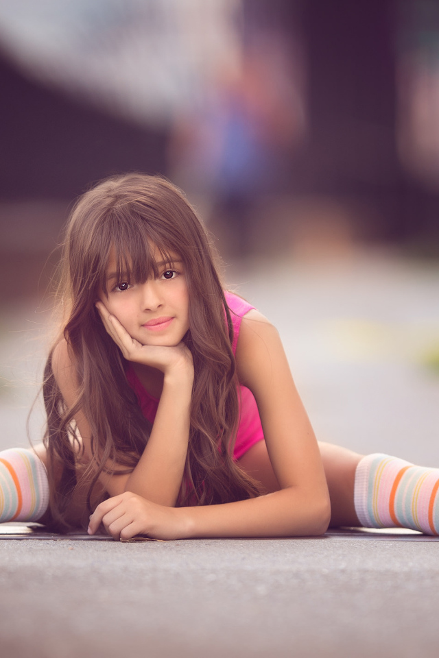 Маленькая девочка сидит на дороге в роликах