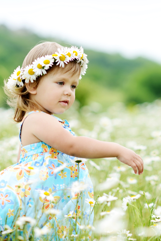 Маленькая девочка с венком на голове гуляет по полю с ромашками