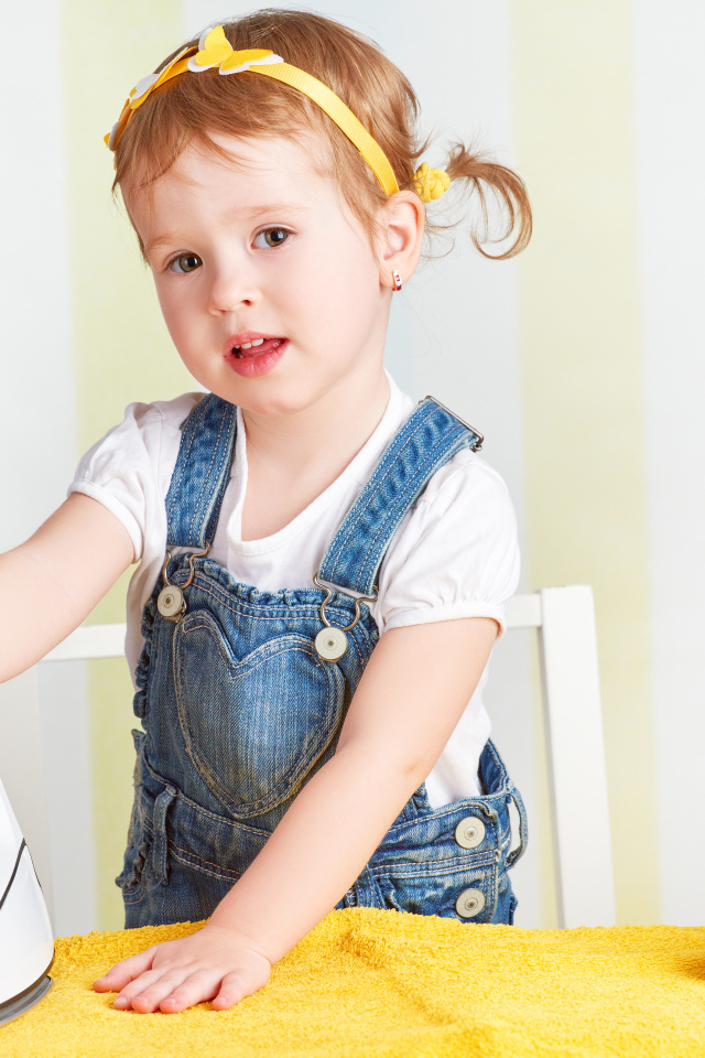 Маленькая девочка с утюгом гладит полотенце