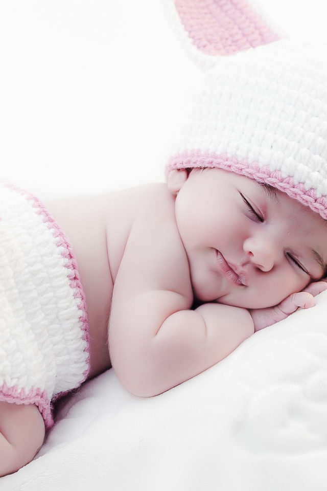 Маленький спящий ребенок в вязаном костюме зайчика