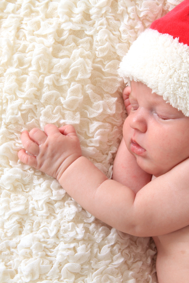 Маленький спящий ребенок в красном новогоднем колпаке