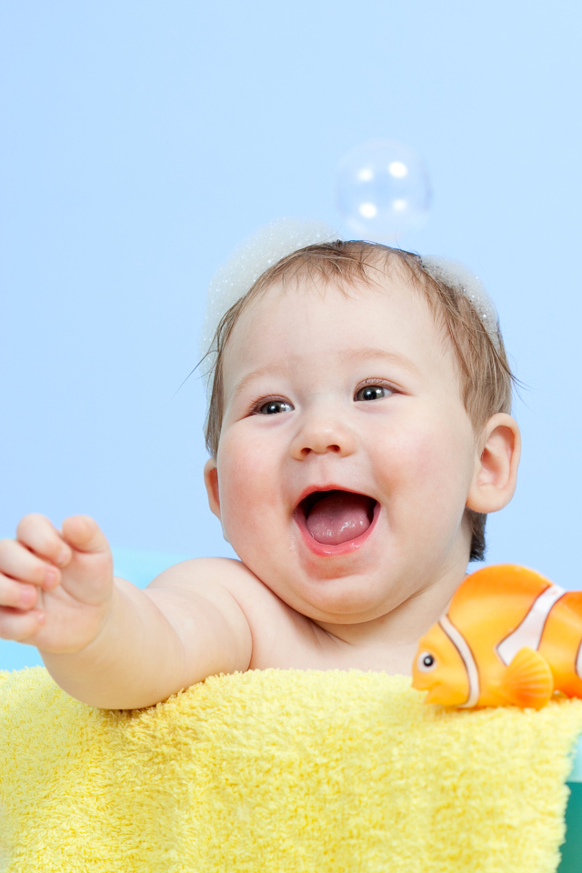 Веселый малыш купается в ванной с игрушечной рыбкой