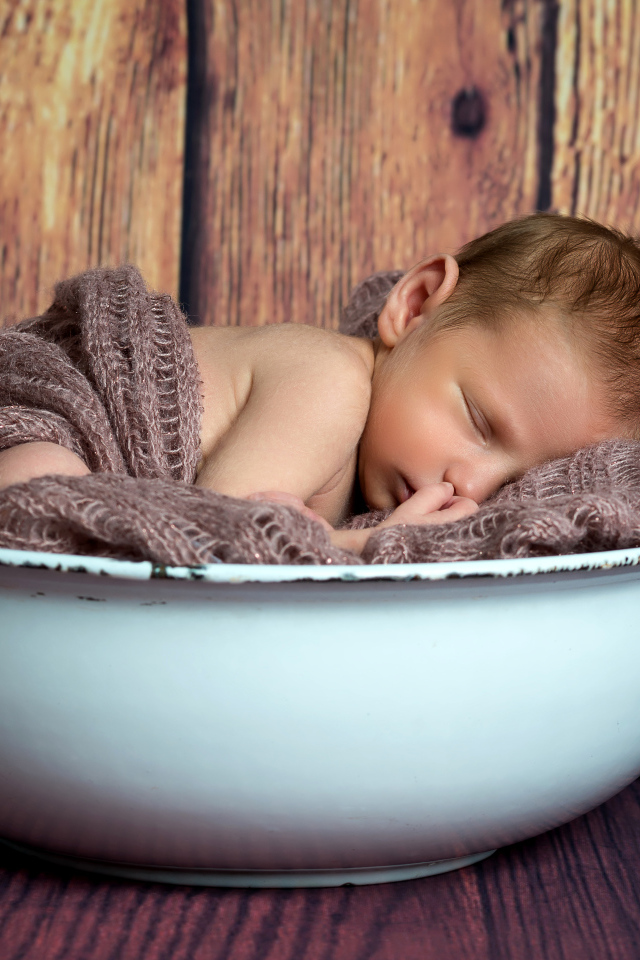 Новорожденный ребенок спит в белой миске