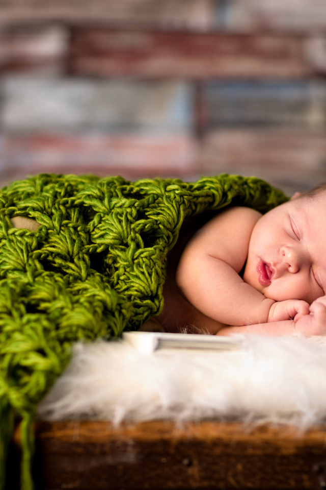 Спящий младенец под зеленым вязаным пледом
