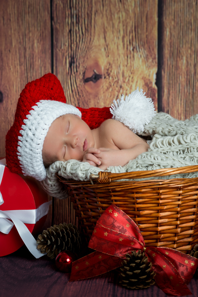 Маленький грудной ребенок спит в плетеной корзине с новогодними подарками