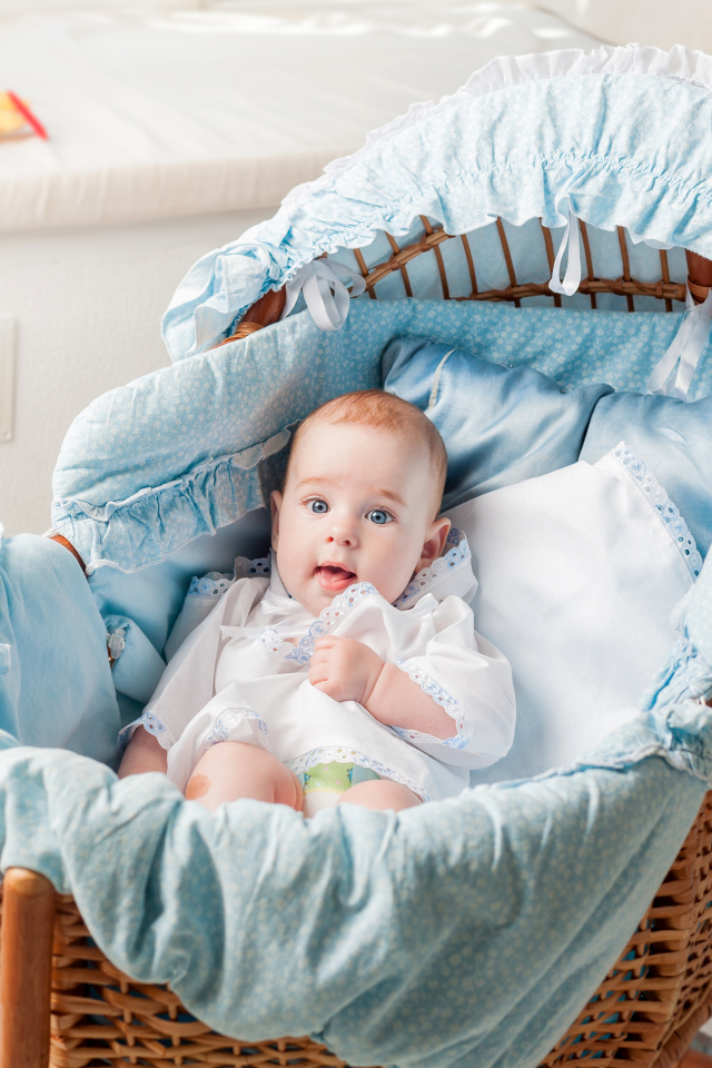 Маленький голубоглазый младенец в кроватке