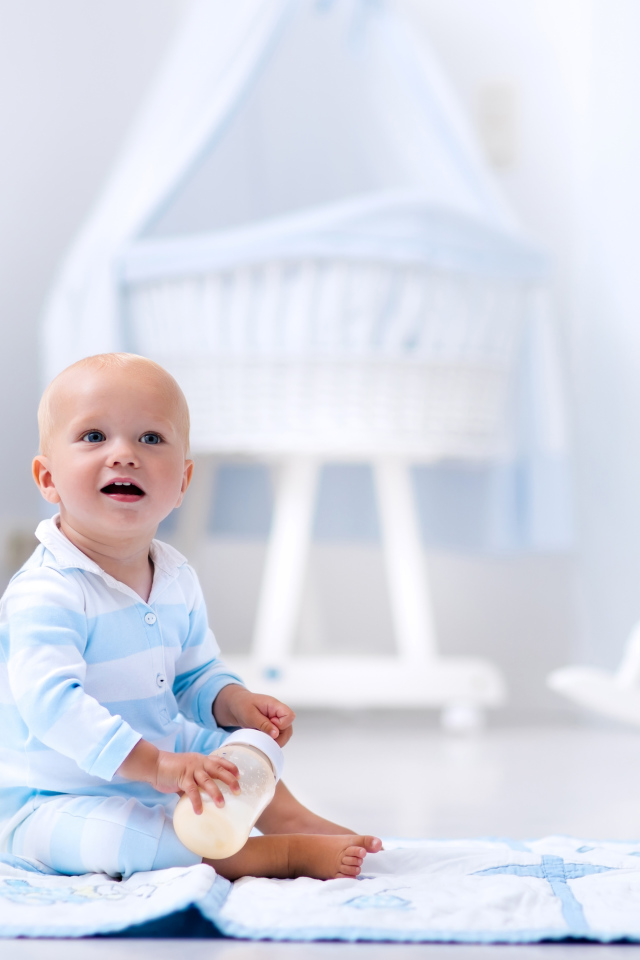 Маленький голубоглазый мальчик сидит на полу в комнате