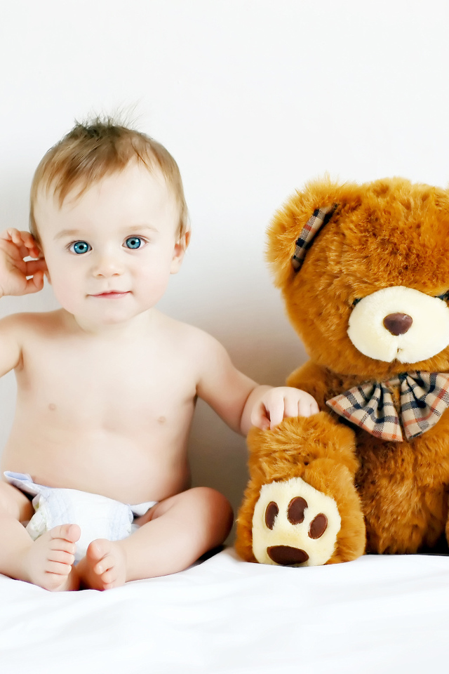 Маленький голубоглазый ребенок с большим плюшевым медведем