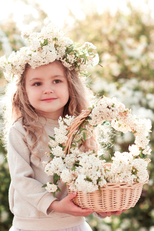 Милая маленькая девочка с венком на голове и корзиной белых цветов