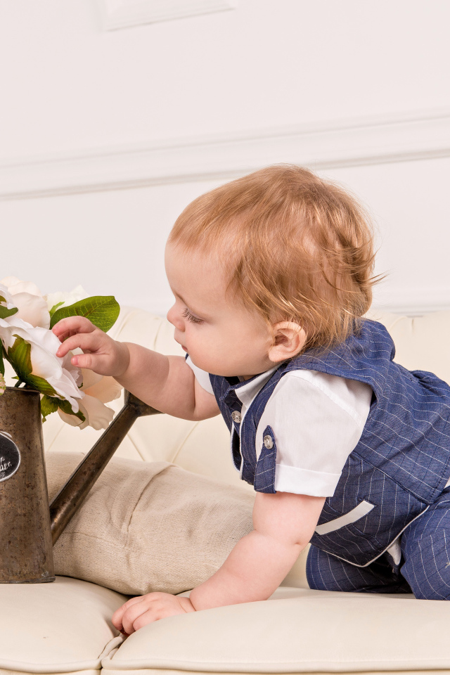 Маленький ребенок рассматривает цветы в железной лейке