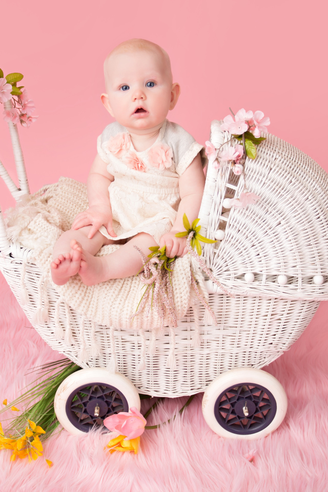 Младенец девочка сидит в коляске на розовом фоне