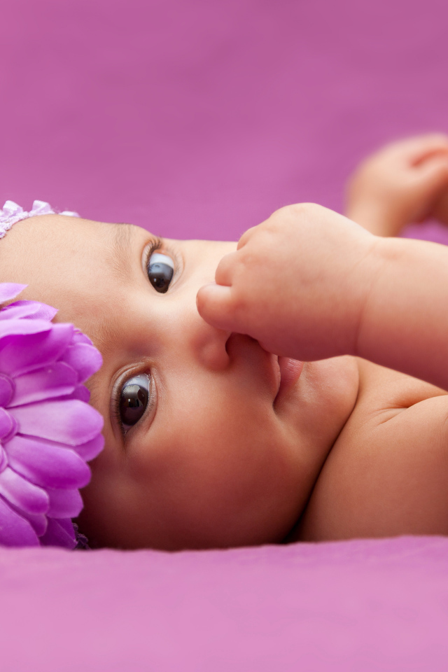 Младенец девочка с большим сиреневым цветком на голове 