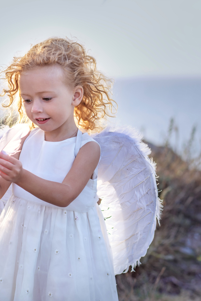 Красивая маленькая девочка в белом платье с крыльями ангела