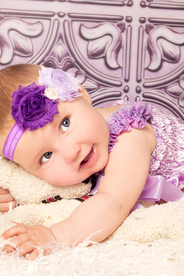 Красивая маленькая девочка в фиолетовом костюме с плюшевым мишкой