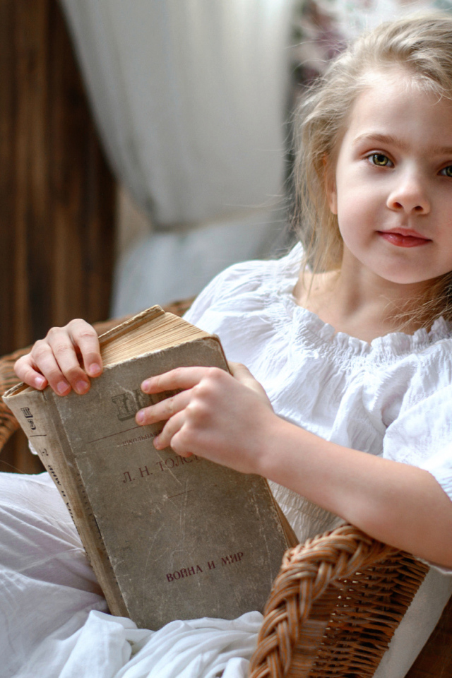 Красивая маленькая девочка в белом платье с книгой 