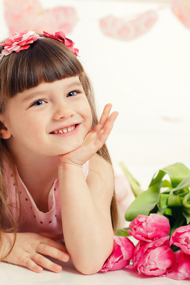 Красивая длинноволосая улыбающаяся девочка с букетом розовых тюльпанов