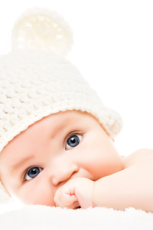 Голубоглазый младенец с белой шапке с ушками на белом фоне