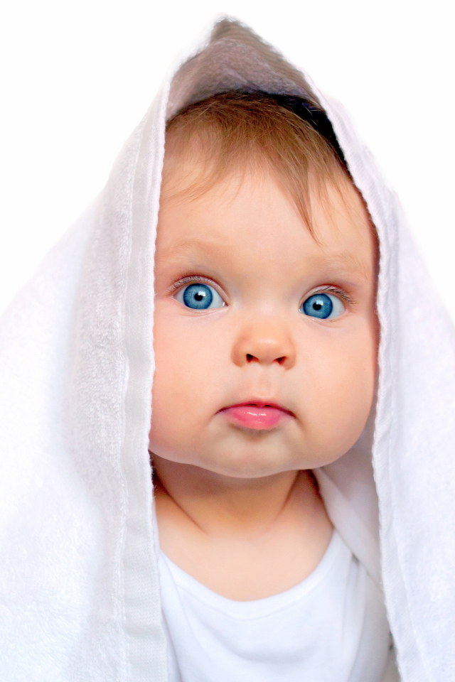 Милый голубоглазый малыш с белом полотенце