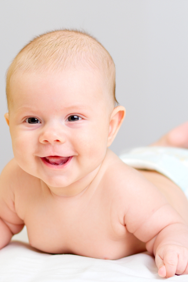 Милый улыбающийся ребенок на сером фоне