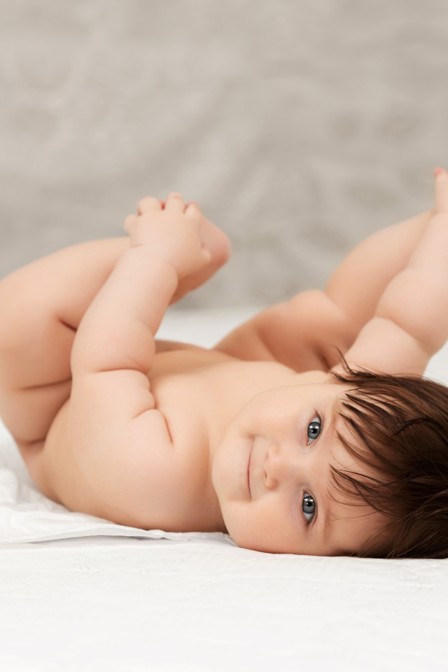 Забавный младенец держится руками за ноги 