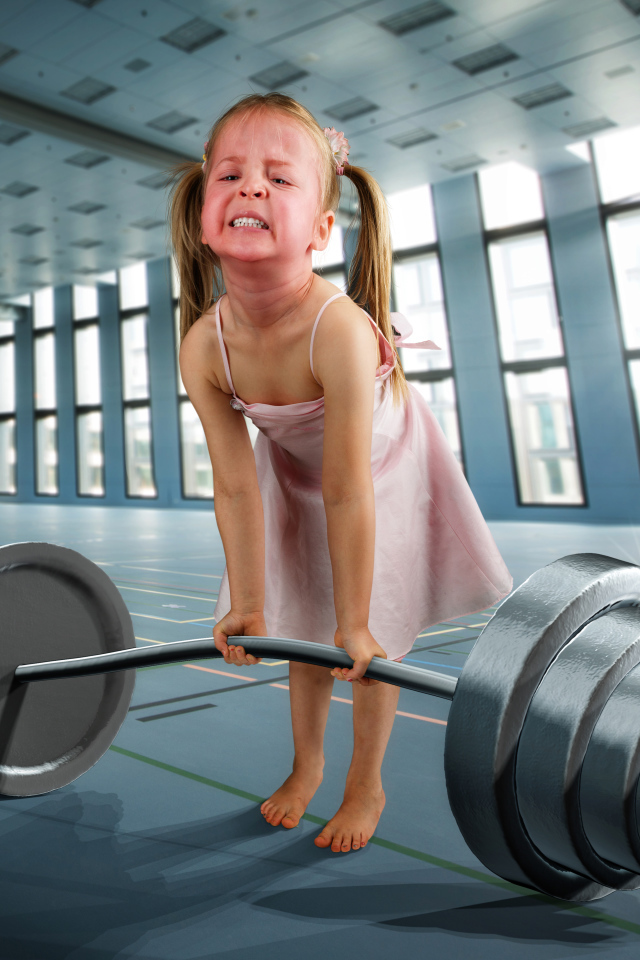 Смешная девочка пытается поднять тяжелую штангу