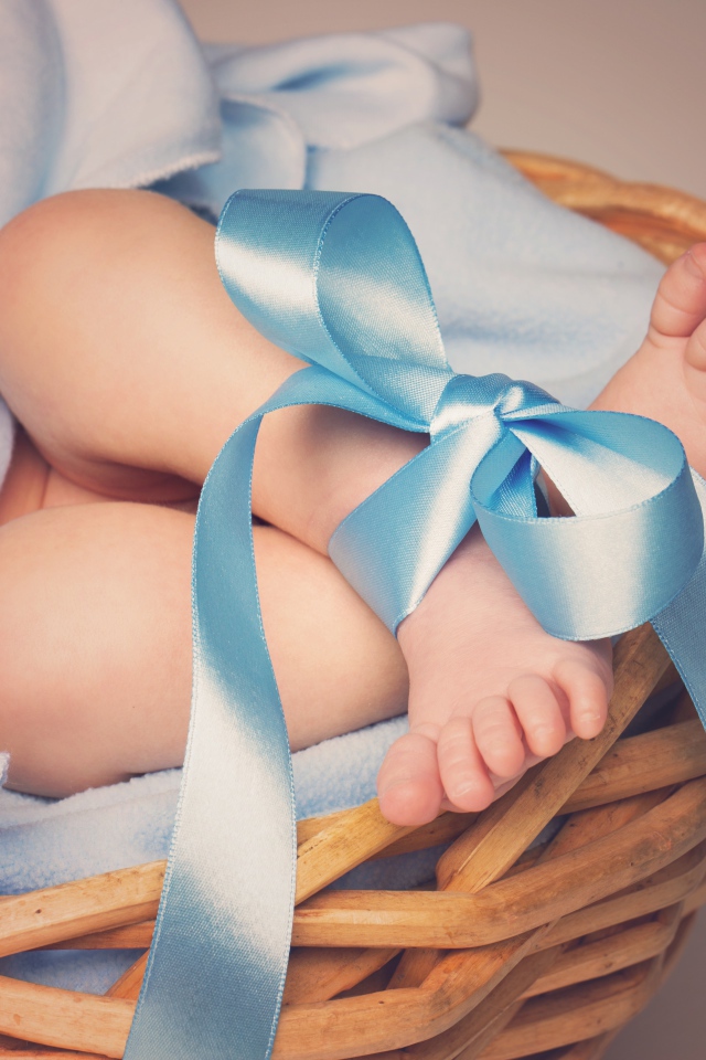 Маленькие ноги младенца с голубым бантом