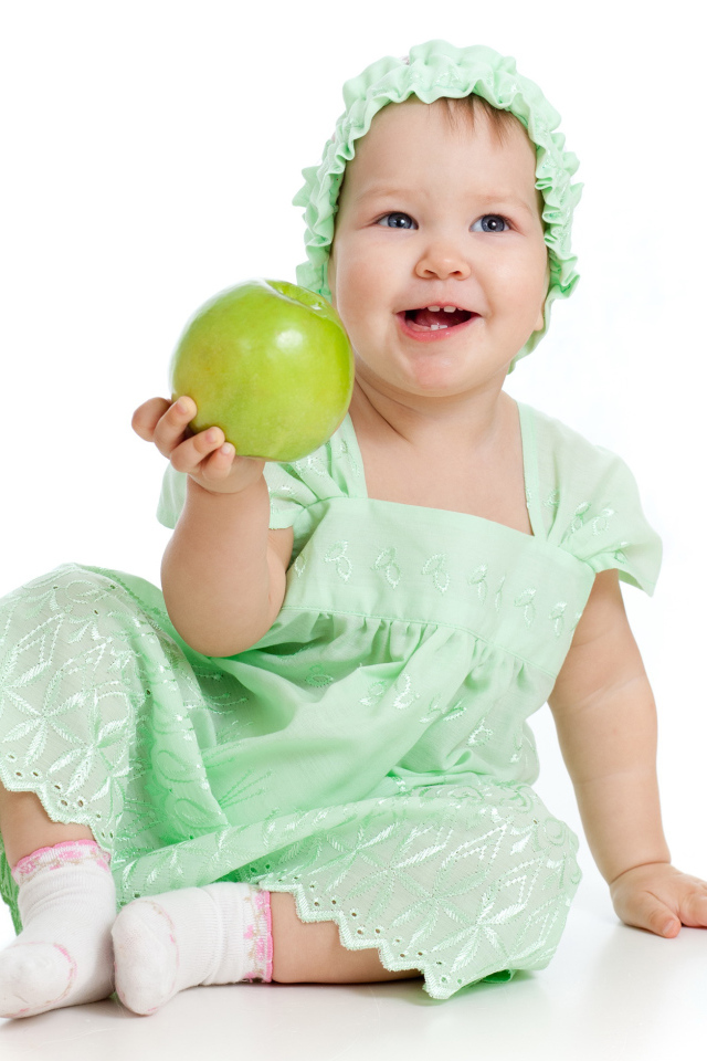 Маленькая голубоглазая девочка с зеленым яблоком в руках