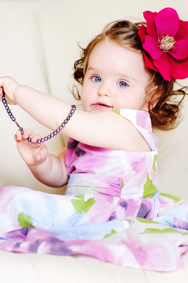 Маленькая голубоглазая девочка с красным цветком в волосах