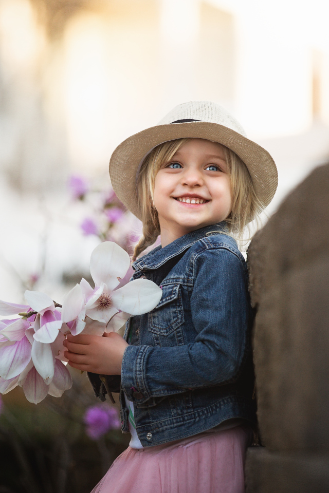 Маленькая голубоглазая улыбающаяся девочка в шляпе с букетом в руках