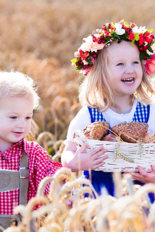 Маленькие мальчик и девочка на поле пшеницы с корзиной свежей выпечки