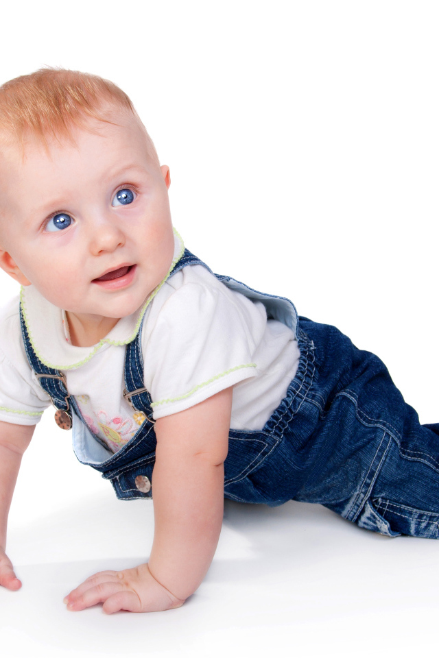 Маленький мальчик в синем комбинезоне на белом фоне