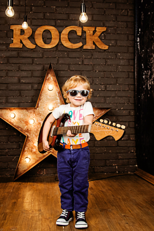 Маленький мальчик в модных очках с гитарой